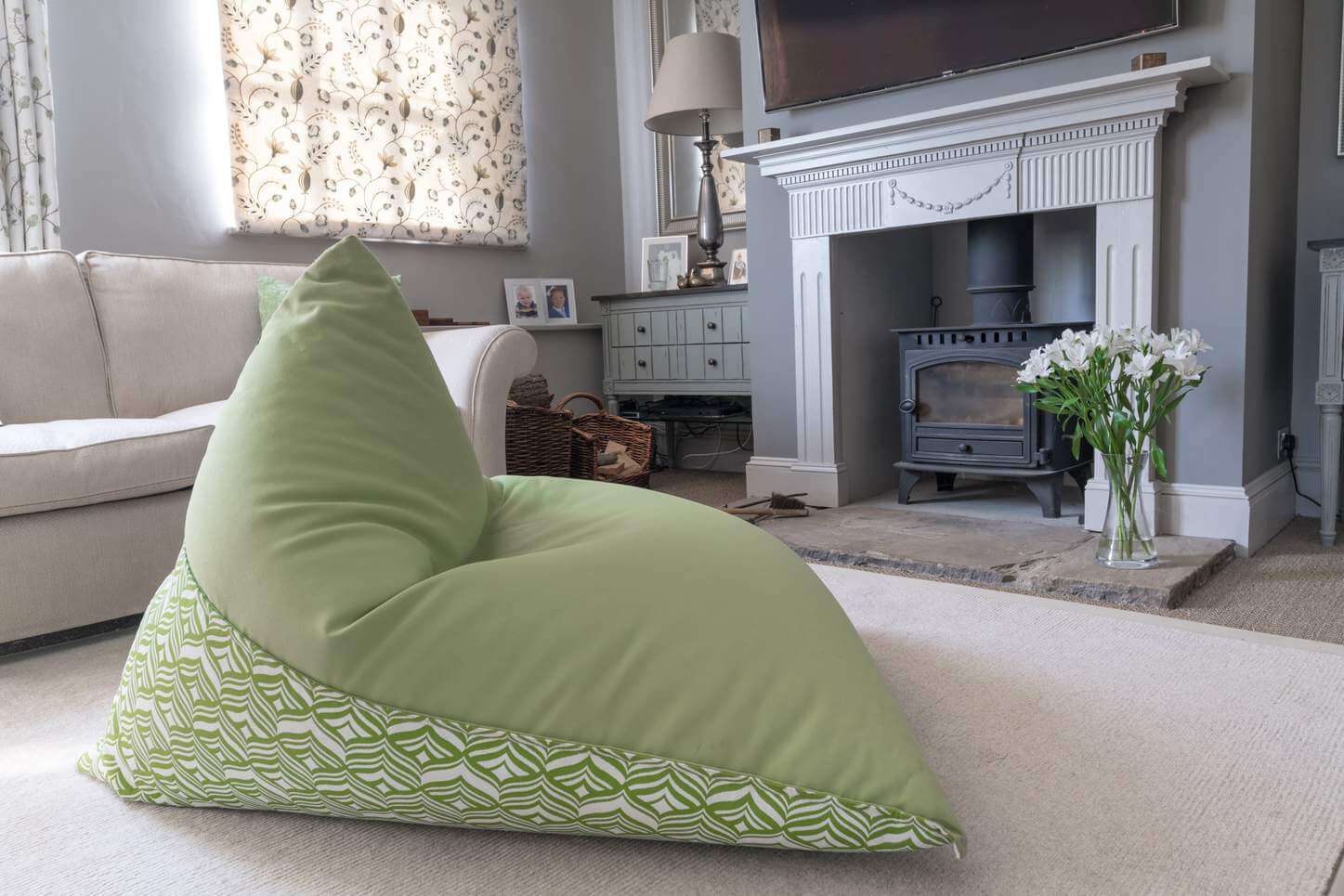 Large light green outdoor bean bag in a living room by the fireplace.