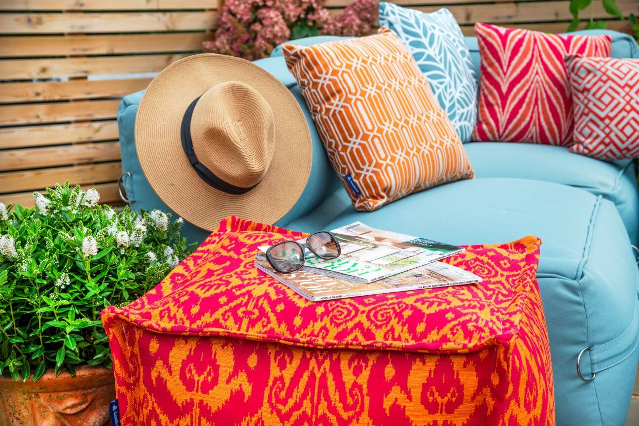 Brightly coloured garden furniture including orange outdoor cushions and blue garden sofa.