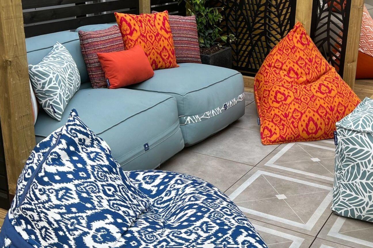 A small patio comforably furnished with two bean bags, a compact outdoor sofa, and a versatile weatherproof pouffe.
