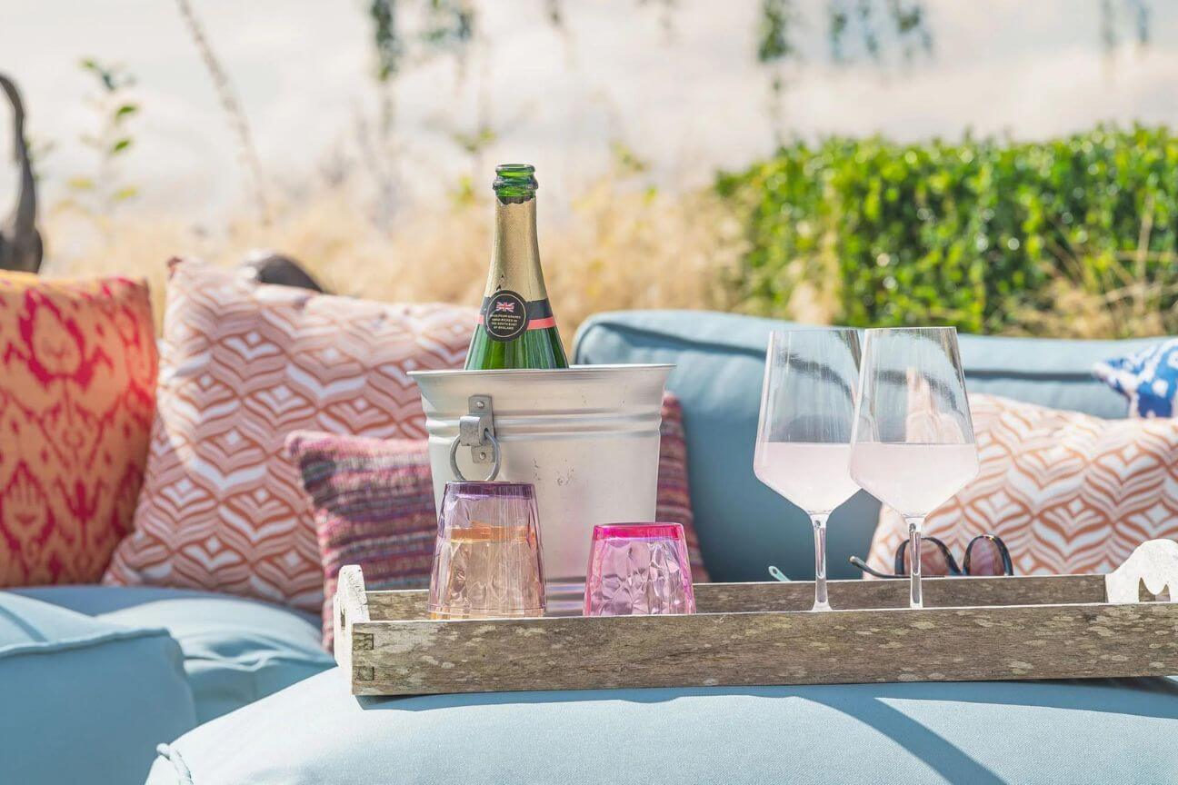 A garden sofa, complete with cushions and bottle of champagne, is ready to host guests at a garden party celebration