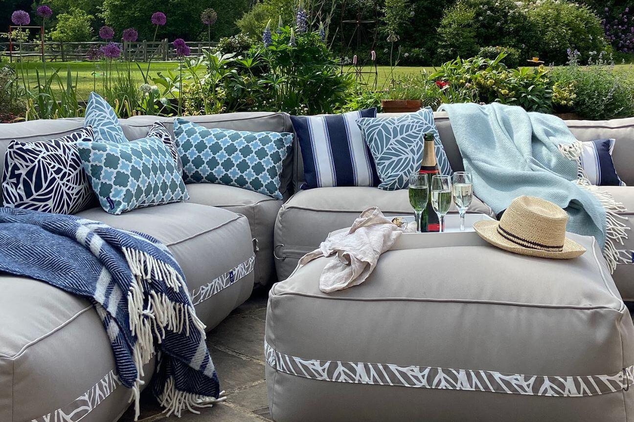 Soft outdoor fabric sofa and patterned and striped garden cushions on a sunny patio.