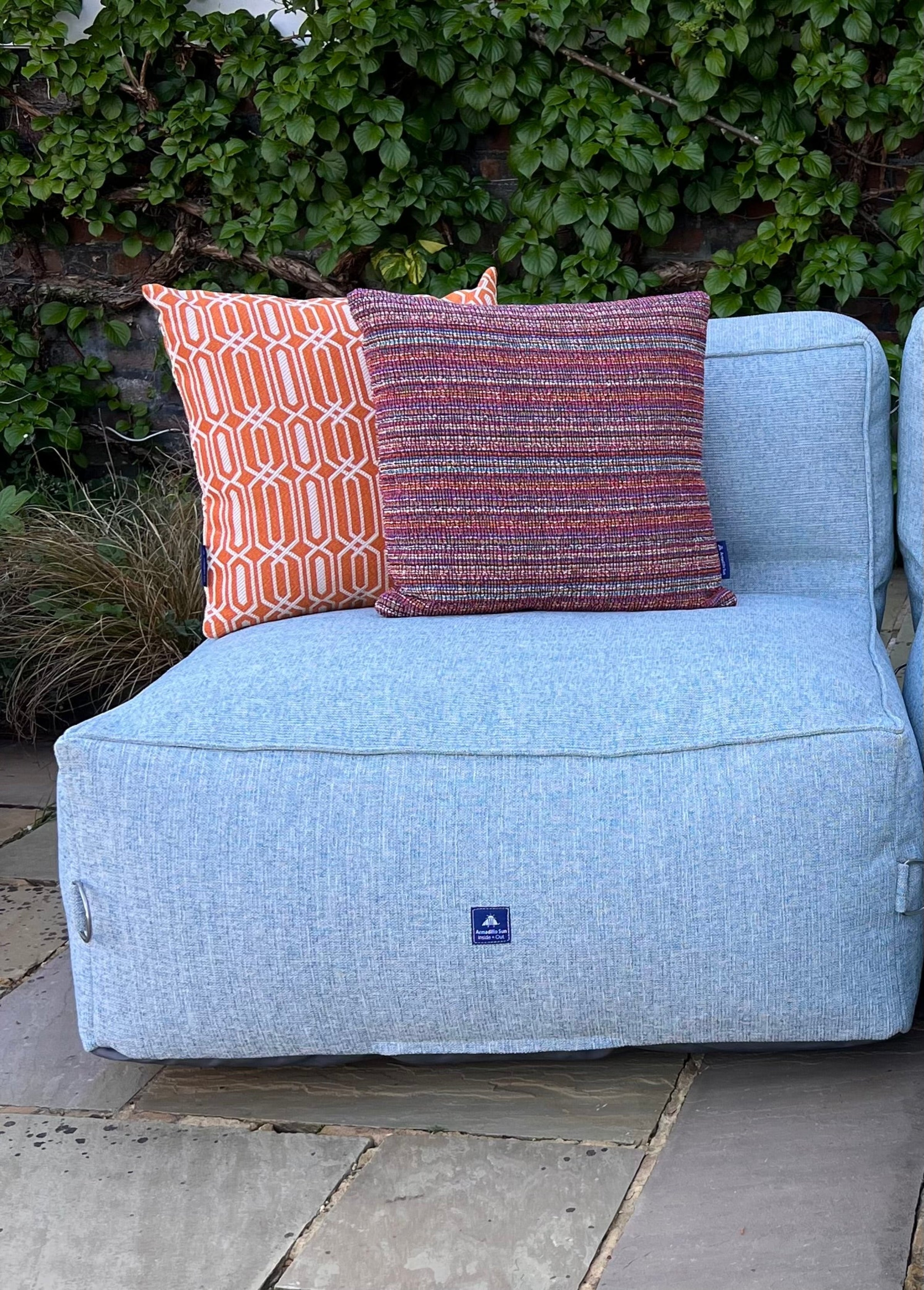 Garden bean bag chair in sea spray decorated with orange calypso and tropic woven cushions. 100% british-made, stain-proof, water-resistant with 5 year guarantee