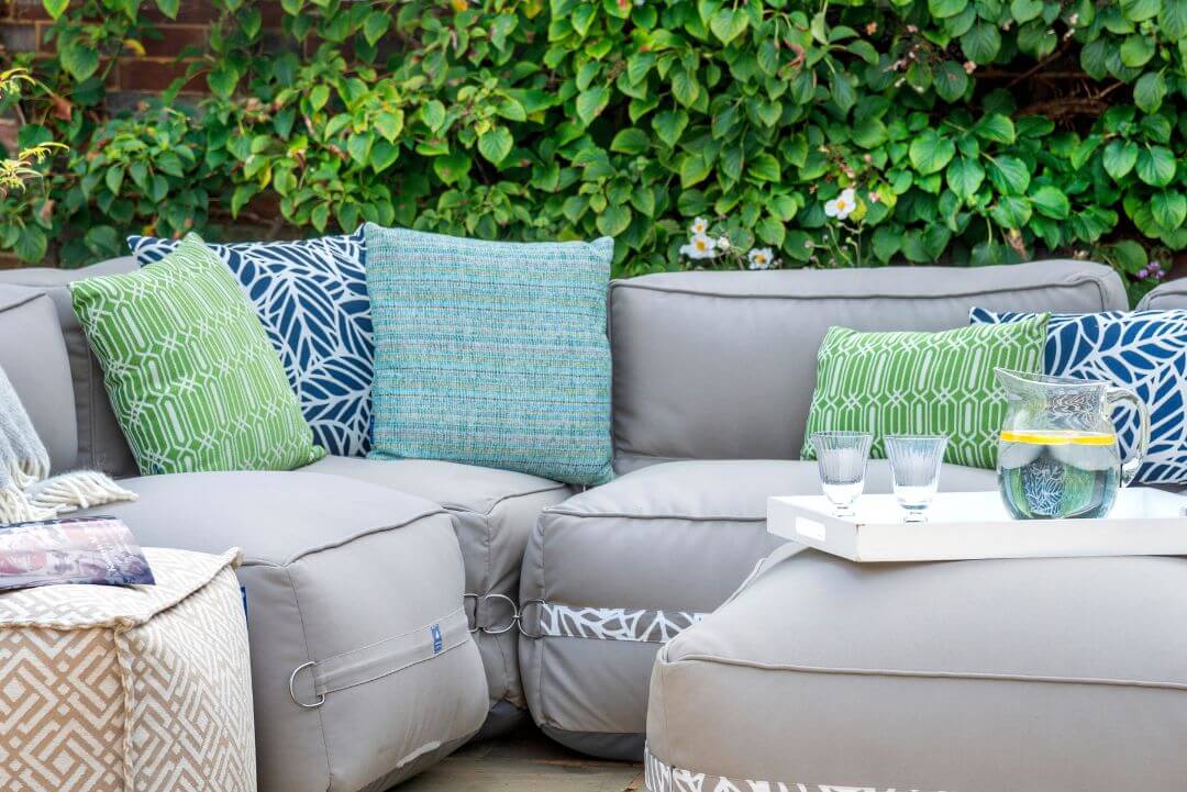 Green patterned outdoor cushions scattered on a garden sofa.