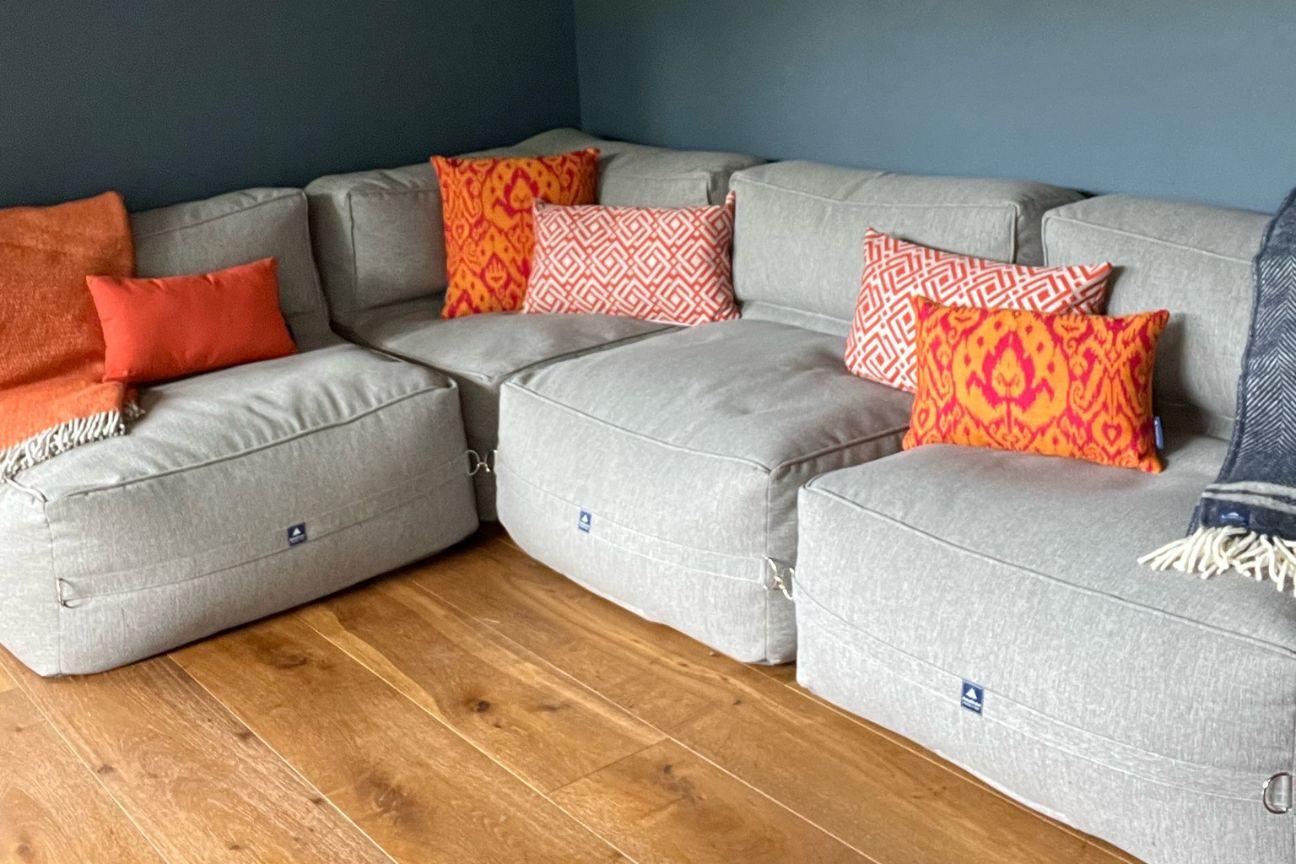 Premium bean bag sofa installed in an awkward corner of a room and covered with patterned throw cushions.