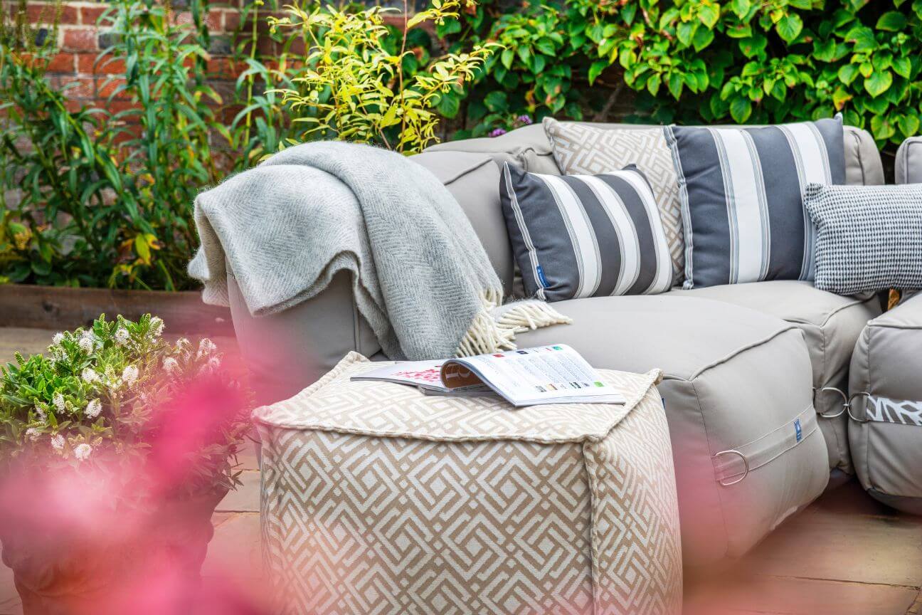 Grey outdoor sofa covered with grey and white striped cushions on a winter patio.