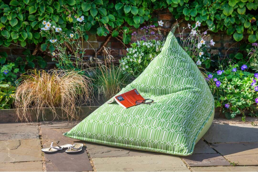 Light green patterned bean bag chair in the sunshine on garden paving.