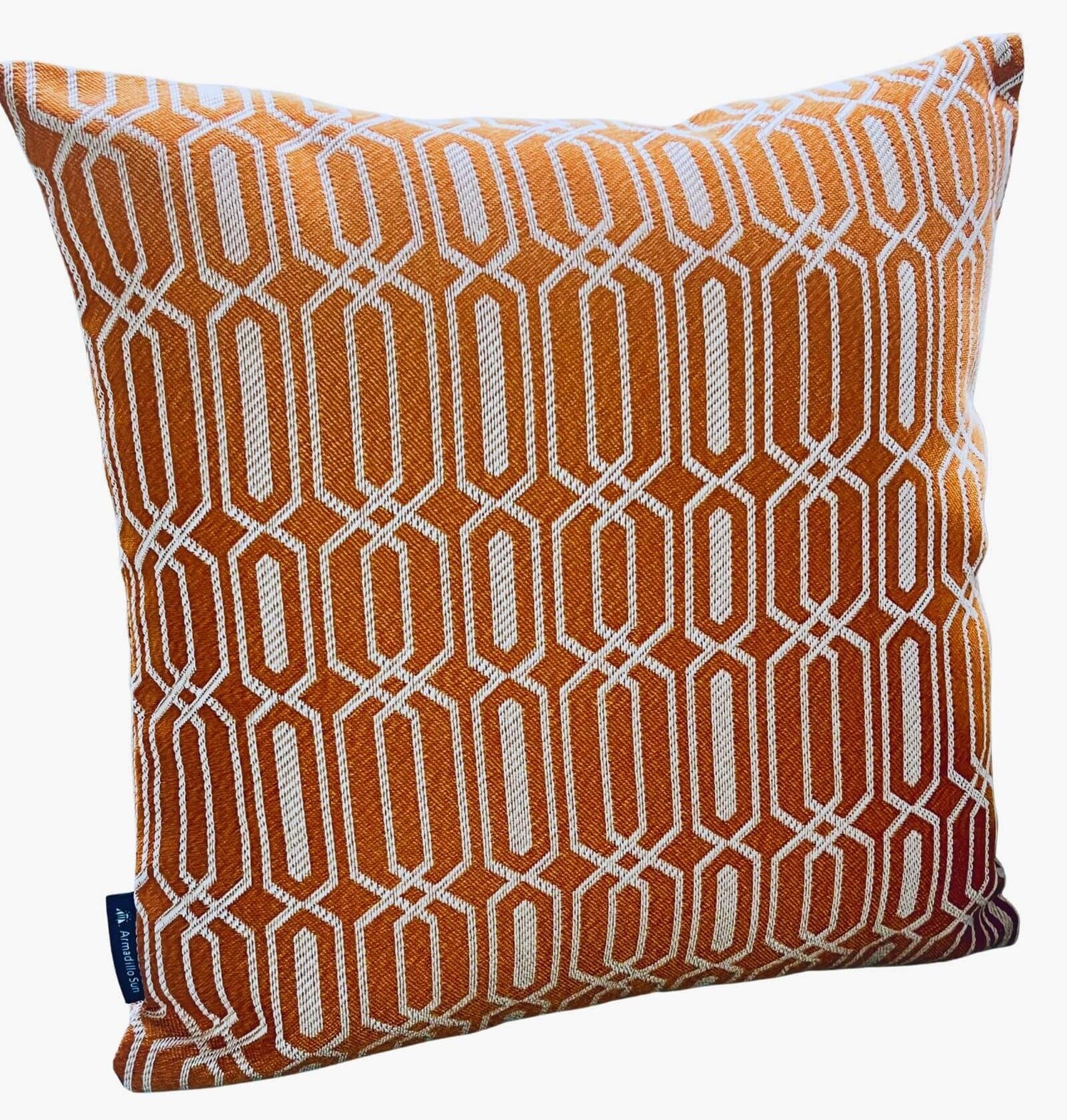 An orange orange cushion woven with a white geometric repeated pattern. 