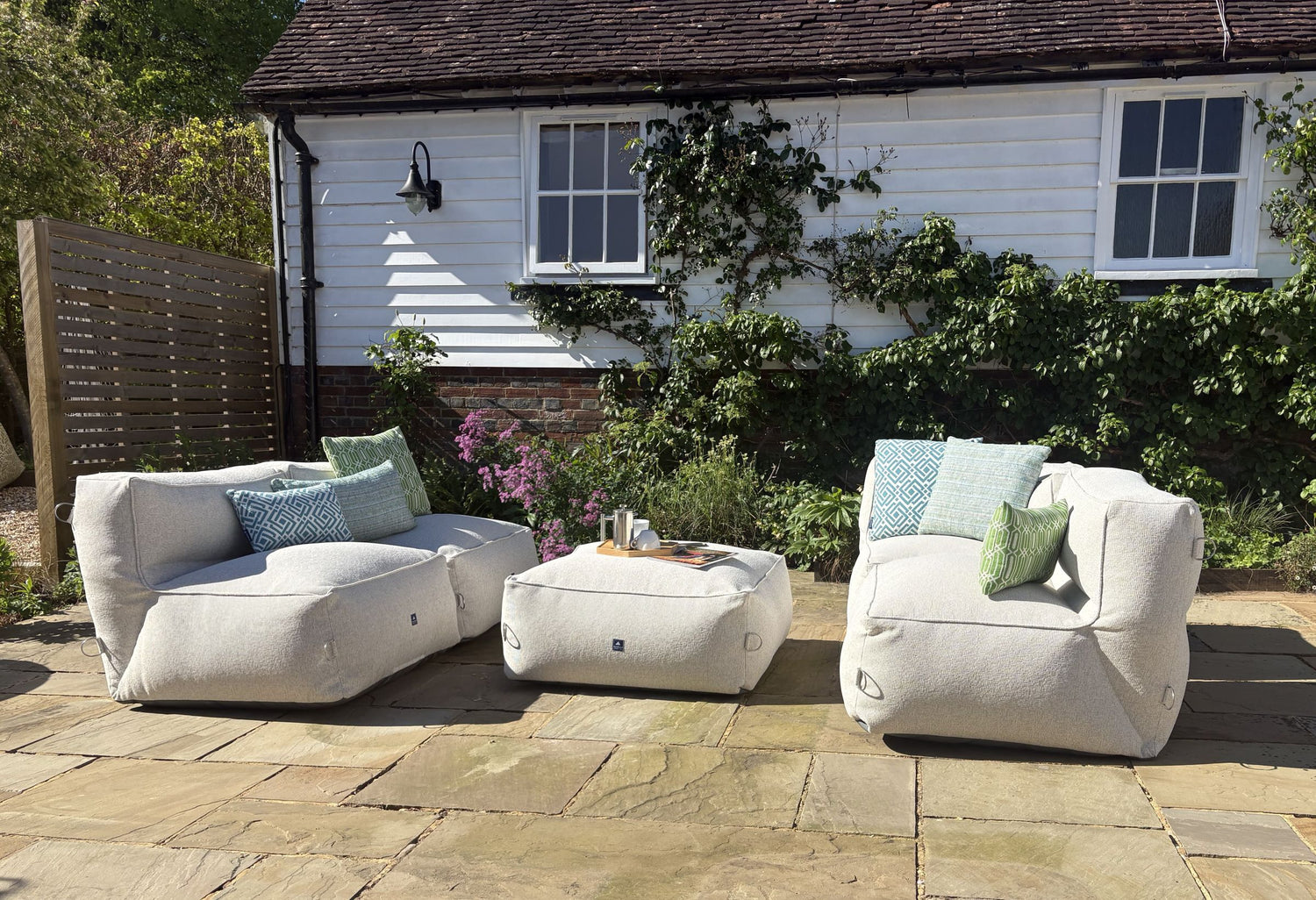 garden bean bag dining sofa set in natural shell consisting of 4 chairs and 1 ottoman. decorated with green and blue cushions in calypso, sigma and woven patterns. water-resistant, stain-proof, 100% british made with 5 year guarantee