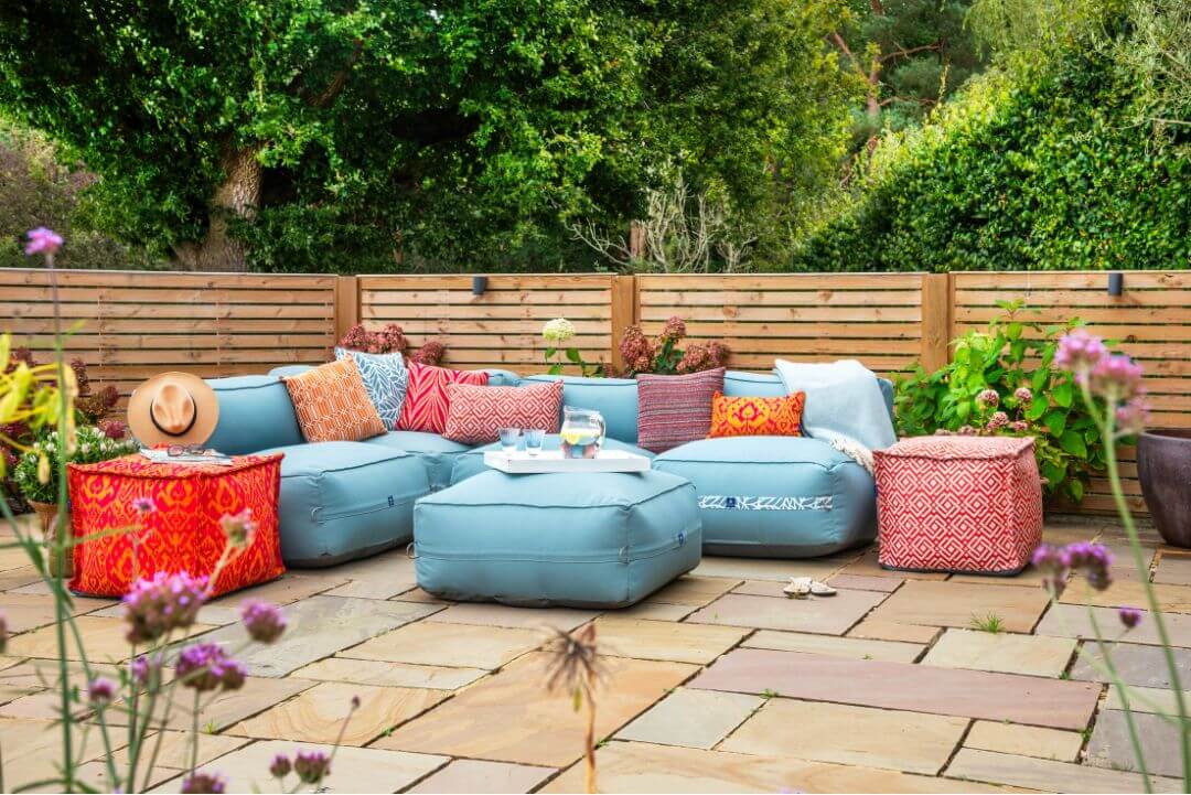 A garden sofa covered with bright patterned cushions.