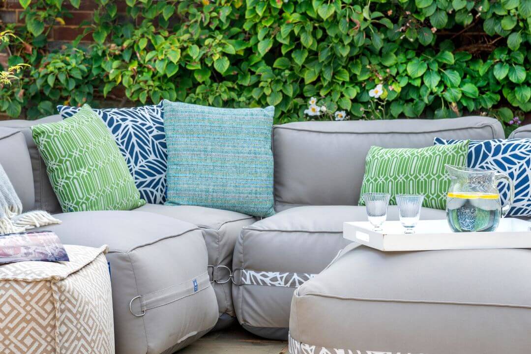 Green patterned outdoor cushions scattered on a garden sofa.