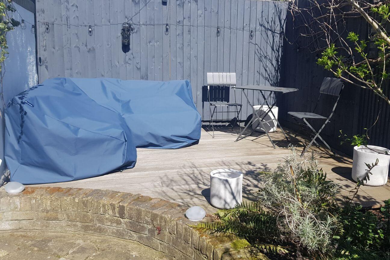 Dark blue waterproof cover over a garden sofa on a winter patio